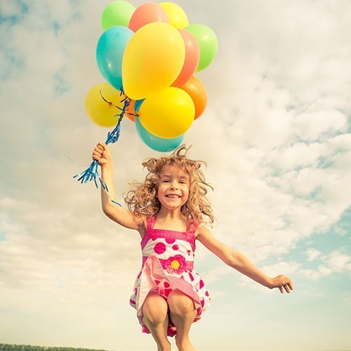 nena saltando feliz con globos